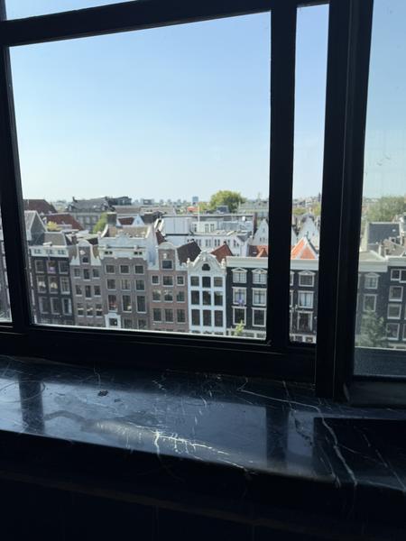 This photo captures a panoramic view of the historic Amsterdam cityscape from a window, showcasing the distinctive gabled rooftops of buildings along Spuistraat, Centrum
